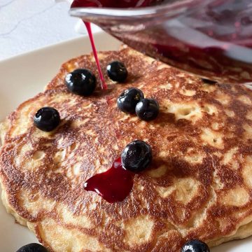 easy oatmeal pancakes with a homemade blueberry pancake syrup being poured over the top