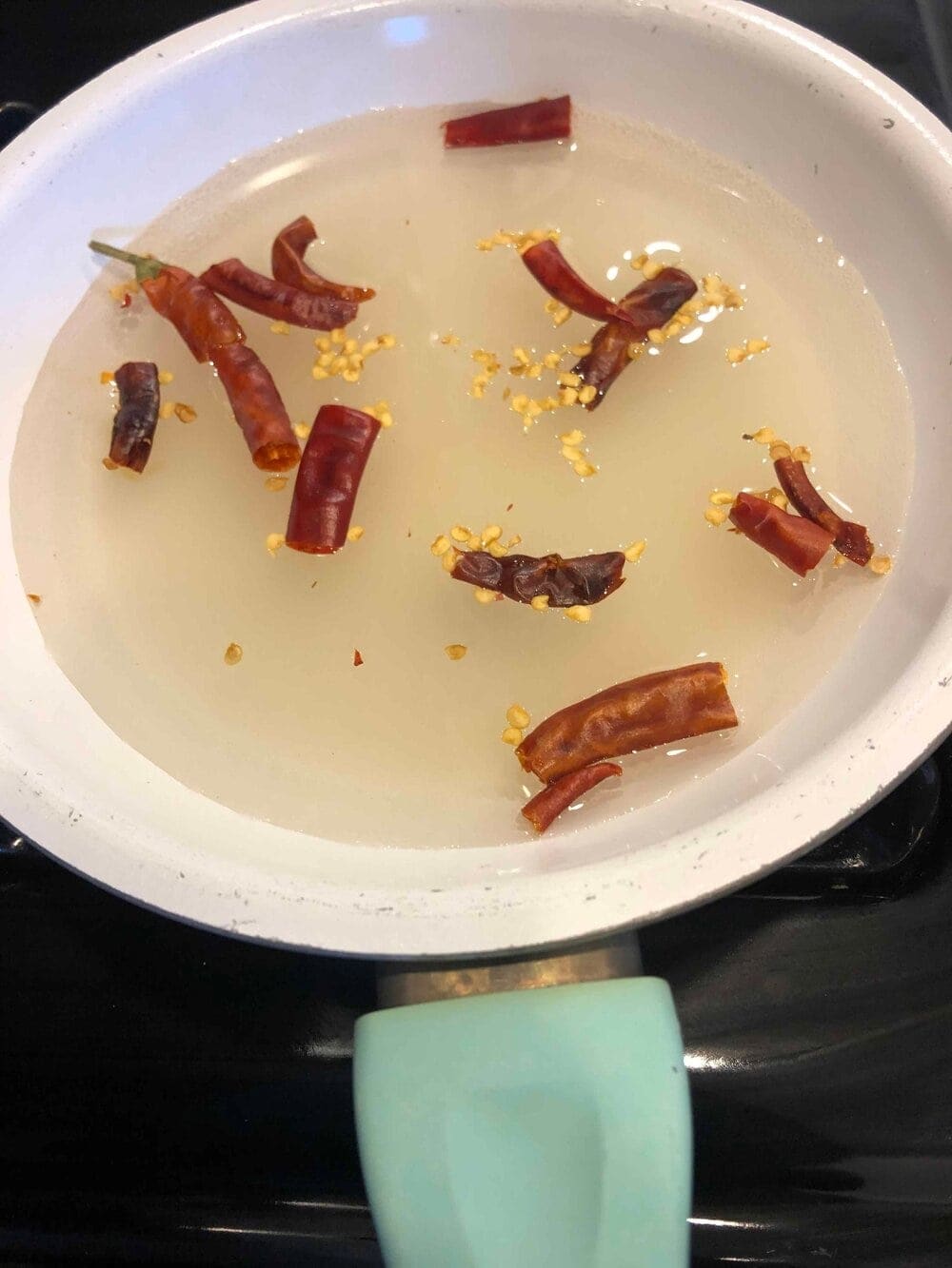 picture on dried chili peppers steeping in a pan of simple syrup to make homemade chili simple syrup
