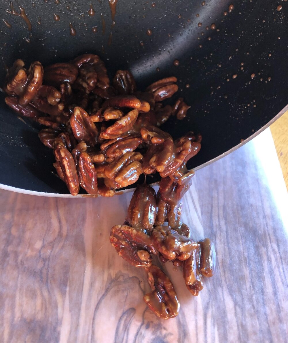 One pot homemade candied pecans that is being poured out of the saucepan