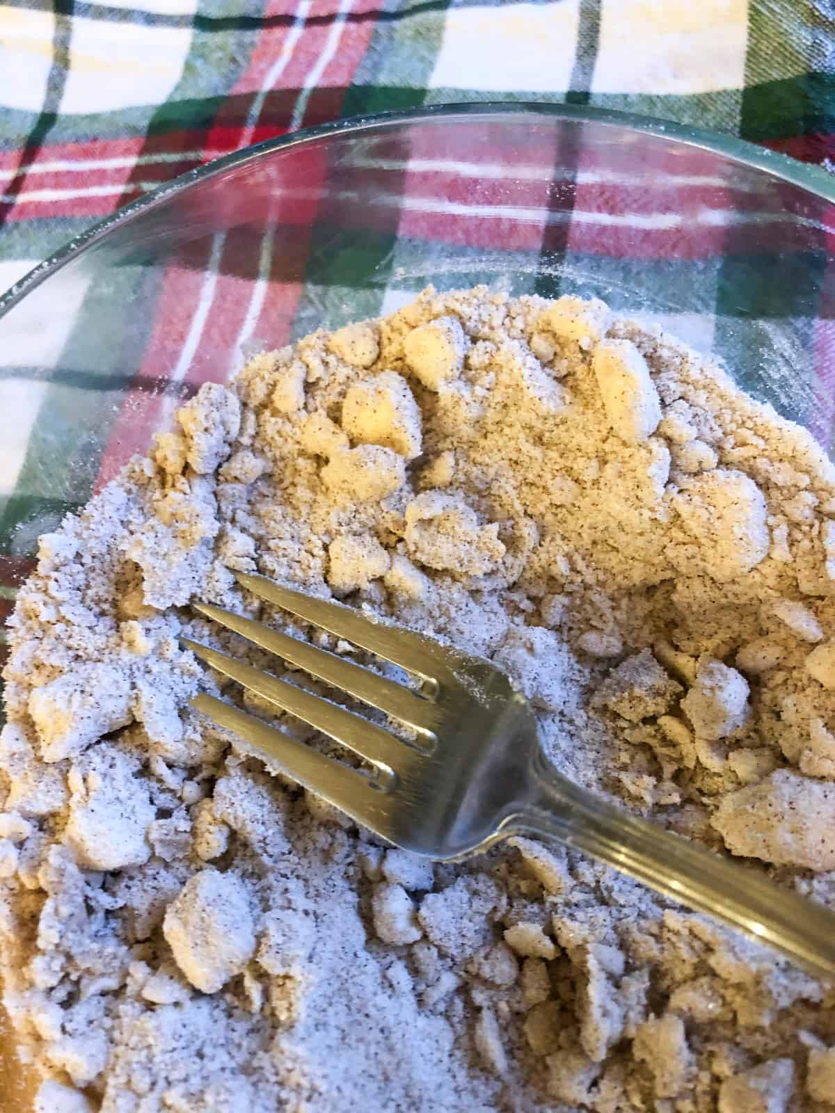 a picture showing how to cut butter into a sugar mixture using a fork to make a streusel topping for blueberry streusel muffins