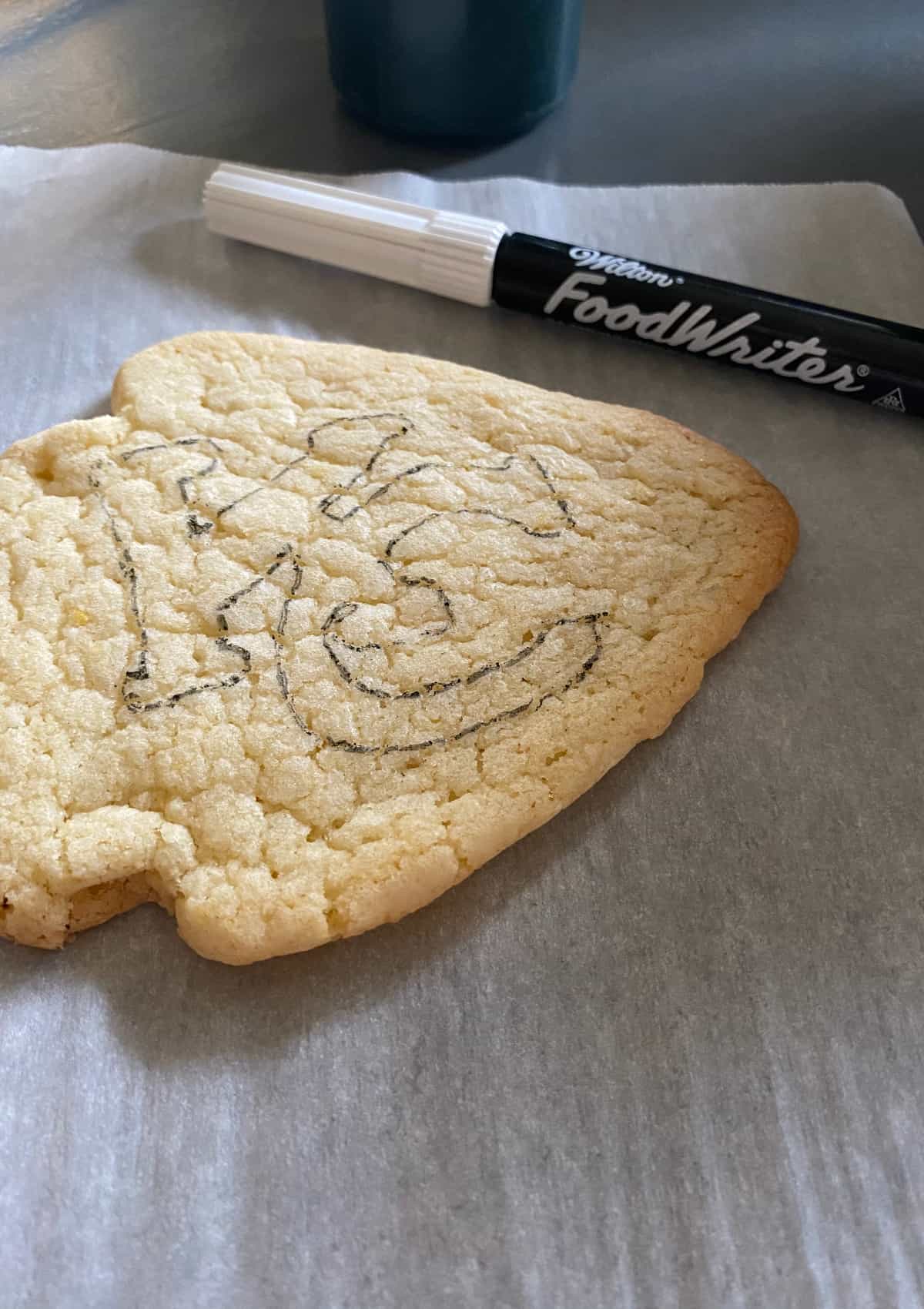 using an icing pen to stencil a logo onto a Chiefs arrowhead sugar cookie
