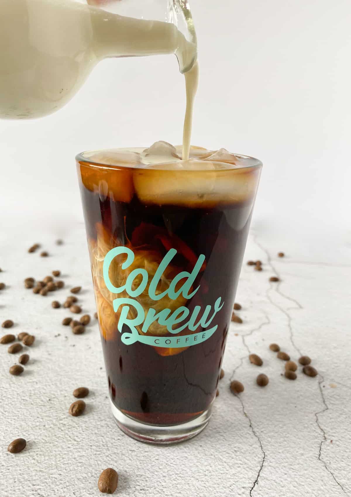 cold brew coffee in a cold brew coffee logo cup with cream being poured over the top
