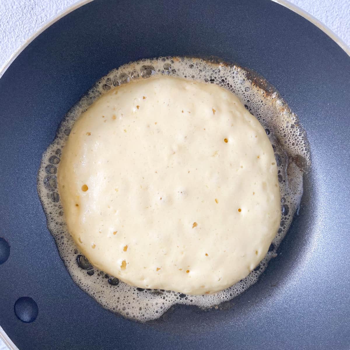 shows a perfectly bubbly olive oil buttermilk pancake that is ready to be flipped
