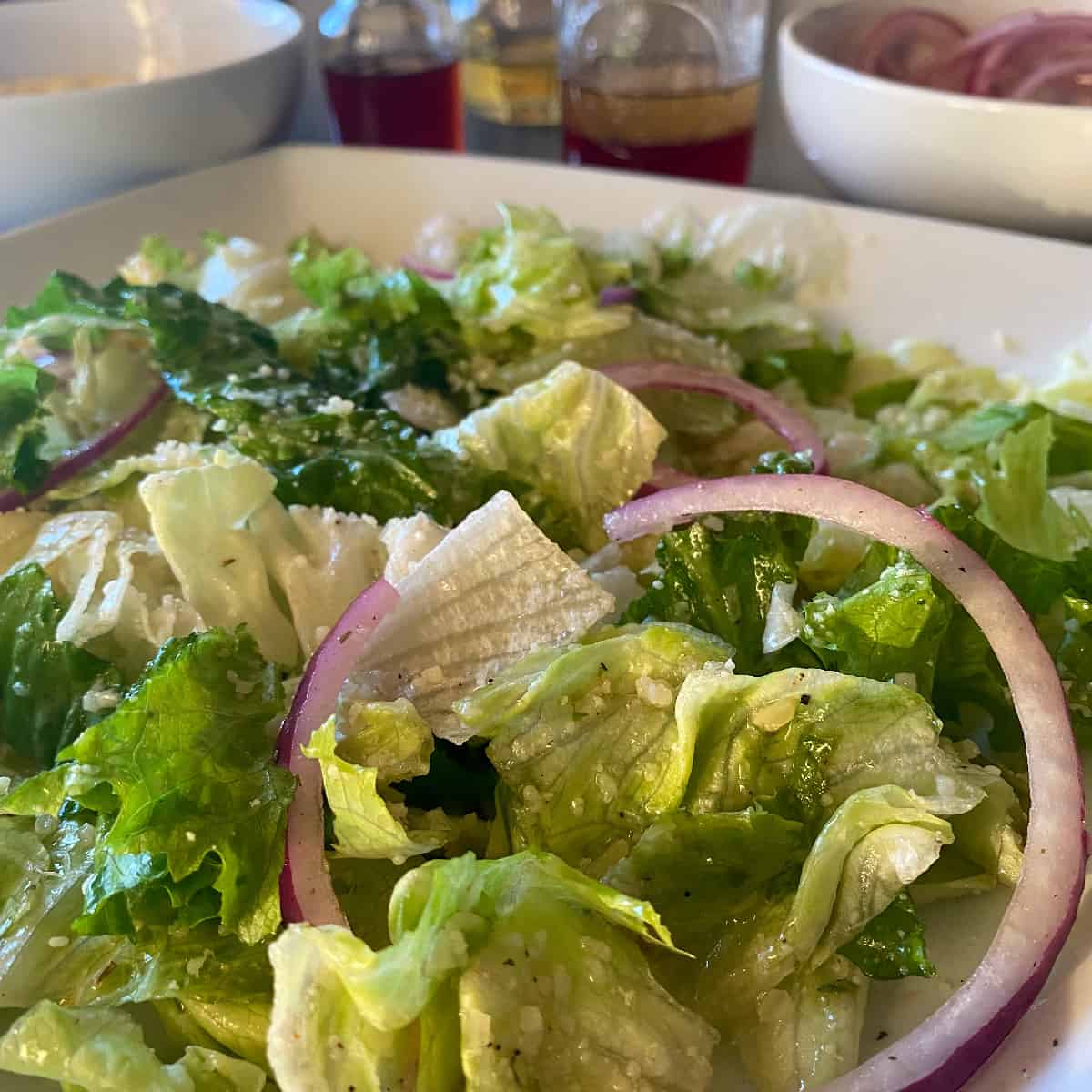 copycat Pasta Express salad with homemade Italian salad dressing ingredients in the background